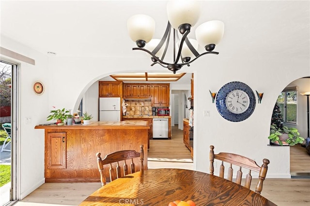 dining room with light wood-style flooring, baseboards, and an inviting chandelier