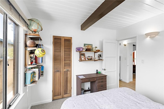 bedroom featuring a closet, light colored carpet, and beamed ceiling