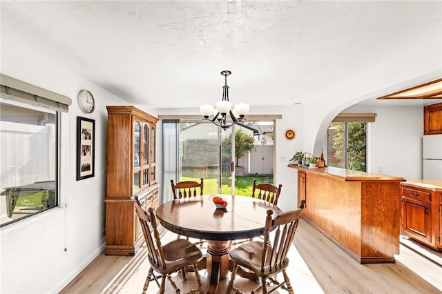 dining area with light wood-type flooring and a chandelier