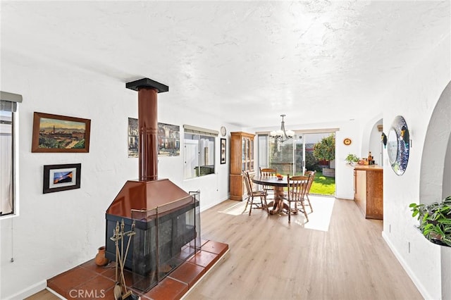 dining space featuring baseboards, a textured ceiling, wood finished floors, and a wood stove