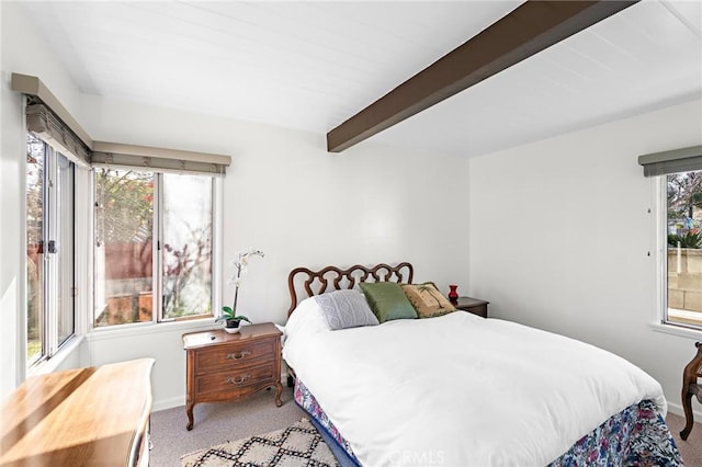 bedroom with baseboards, beam ceiling, and light colored carpet