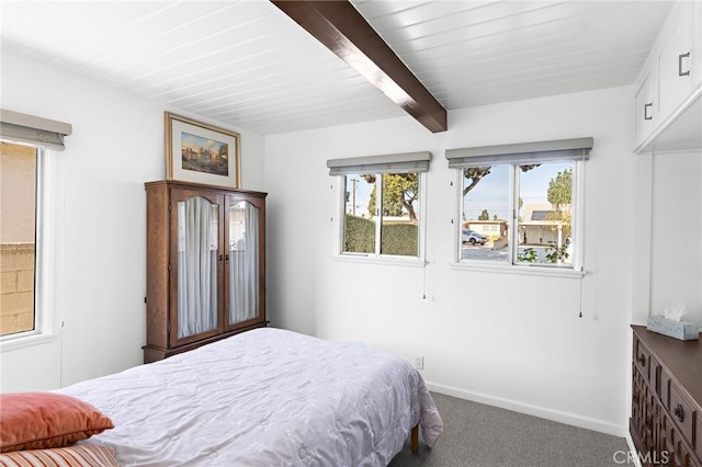 bedroom featuring carpet floors, beamed ceiling, and multiple windows