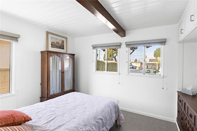 carpeted bedroom featuring beamed ceiling and baseboards