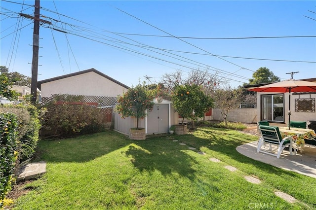 view of yard featuring an outbuilding, a storage shed, a fenced backyard, and a patio area