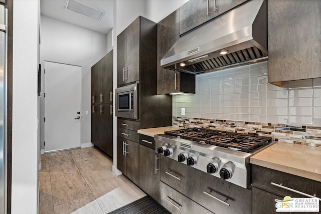 kitchen featuring appliances with stainless steel finishes, dark brown cabinets, and backsplash