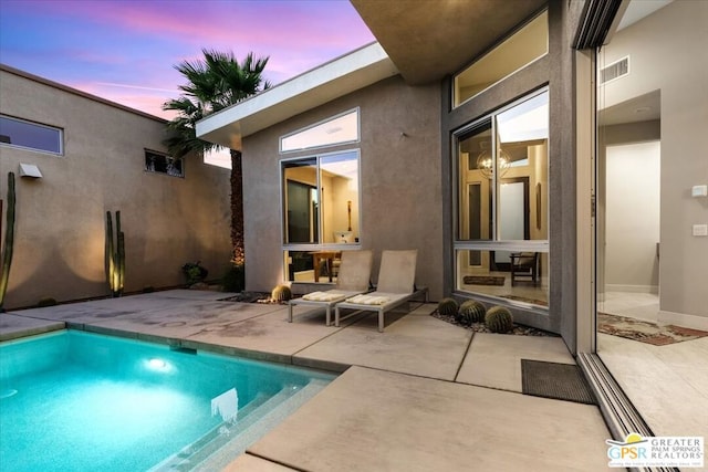 pool at dusk featuring a patio