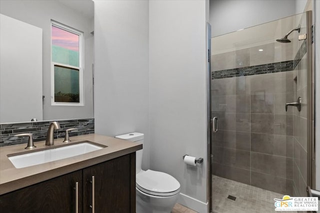 bathroom with toilet, vanity, decorative backsplash, and walk in shower