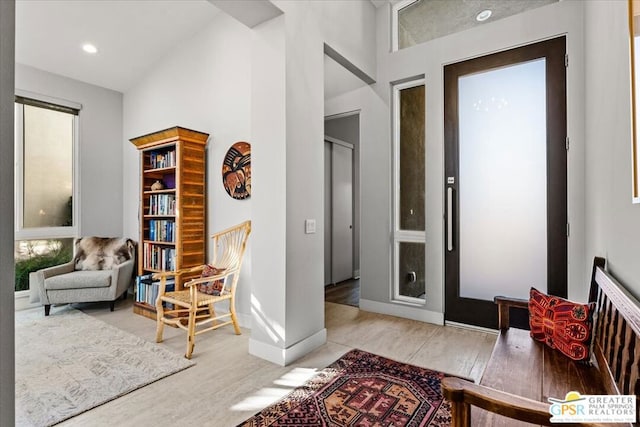 sitting room with high vaulted ceiling and light hardwood / wood-style flooring