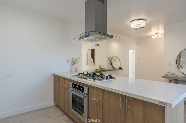 kitchen with stainless steel appliances, light hardwood / wood-style floors, island range hood, and kitchen peninsula