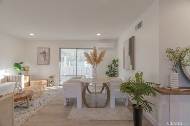 living room featuring light wood-type flooring and a wall mounted air conditioner