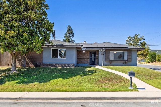 ranch-style home featuring a front lawn and solar panels