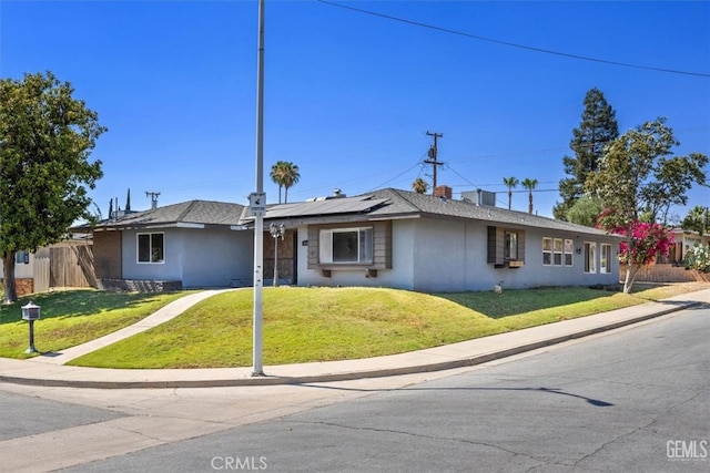 ranch-style house with a front yard and solar panels