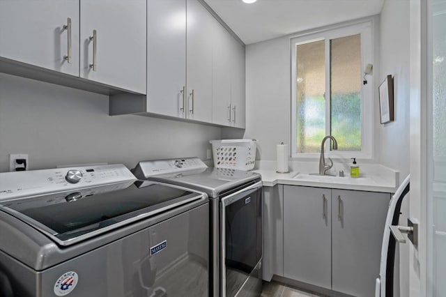 clothes washing area featuring sink, separate washer and dryer, and cabinets