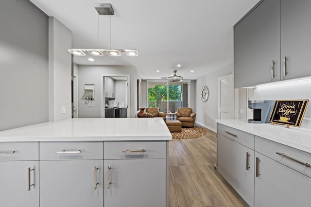 kitchen featuring kitchen peninsula, light wood-type flooring, gray cabinets, and pendant lighting