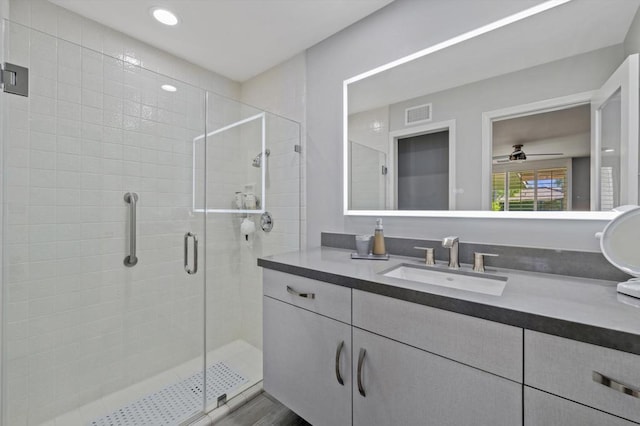 bathroom featuring walk in shower, vanity, and ceiling fan