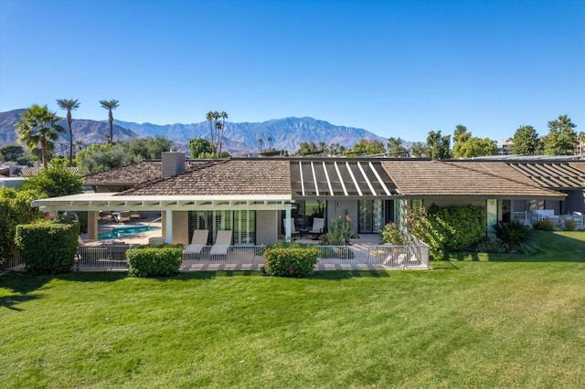 rear view of house with a yard, a mountain view, and a patio