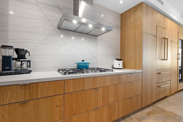 kitchen with decorative backsplash, stainless steel gas stovetop, light stone counters, and ventilation hood