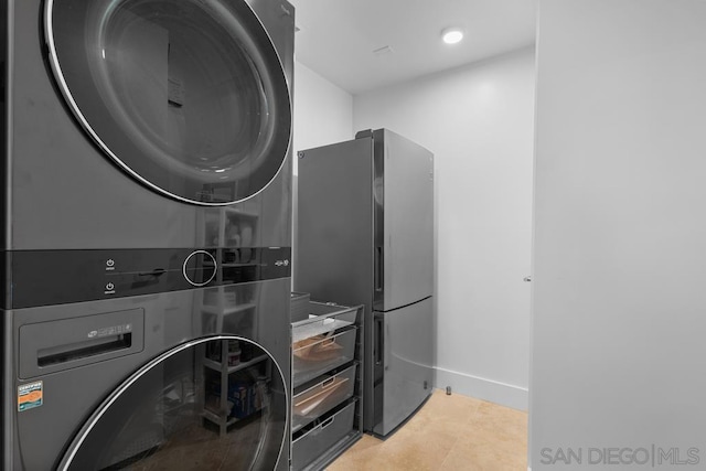 laundry area with stacked washer and clothes dryer and light tile patterned floors