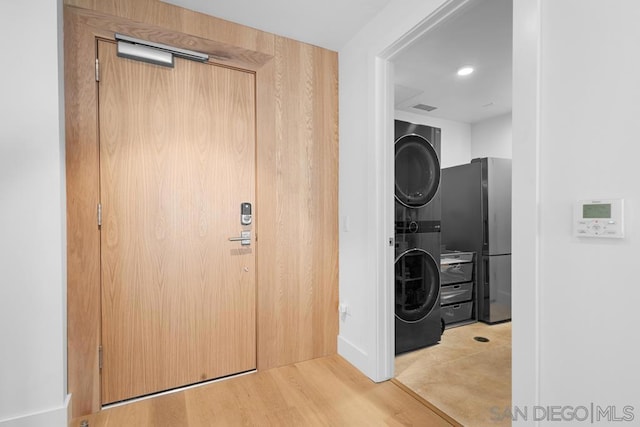 washroom with stacked washer / dryer and light hardwood / wood-style flooring