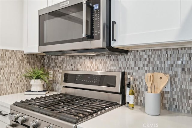 details with tasteful backsplash, white cabinets, and stainless steel appliances