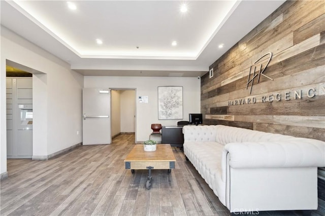 living room featuring a raised ceiling, wood walls, and hardwood / wood-style floors