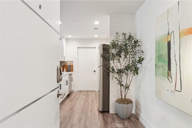 hallway featuring crown molding and light hardwood / wood-style floors