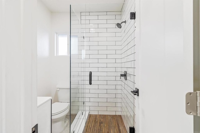 bathroom with a shower with shower door, toilet, and vanity