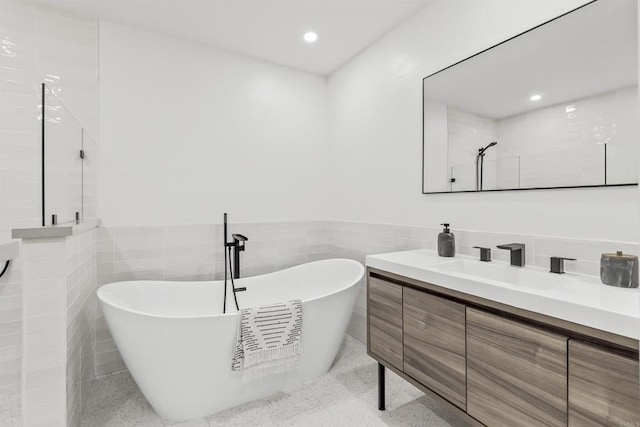 bathroom featuring tile walls, a bathtub, and vanity