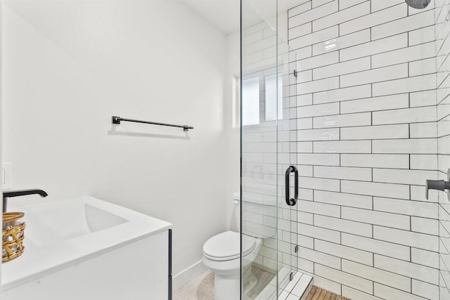 bathroom featuring toilet, a shower with shower door, and vanity