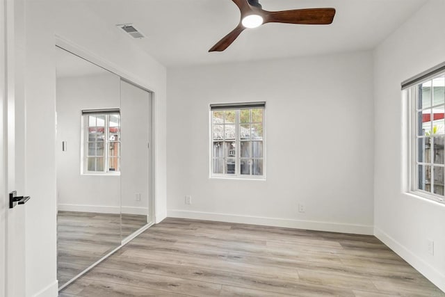 unfurnished bedroom featuring ceiling fan, light hardwood / wood-style floors, and a closet