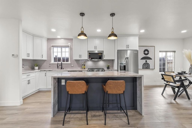 kitchen with white cabinetry, appliances with stainless steel finishes, a center island, and hanging light fixtures