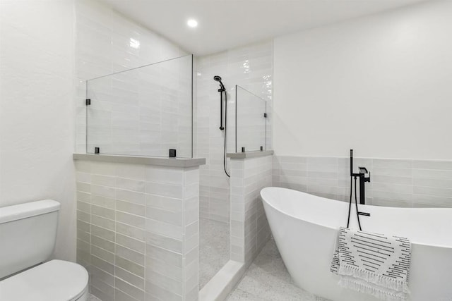 bathroom featuring tile walls, toilet, and separate shower and tub