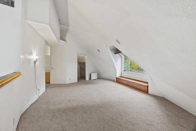 bonus room with carpet, lofted ceiling, and radiator heating unit