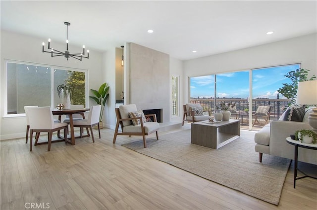 living room with a large fireplace, a wealth of natural light, and light hardwood / wood-style flooring