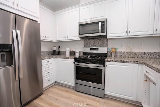 kitchen with white cabinets, stone counters, stainless steel appliances, and light hardwood / wood-style flooring