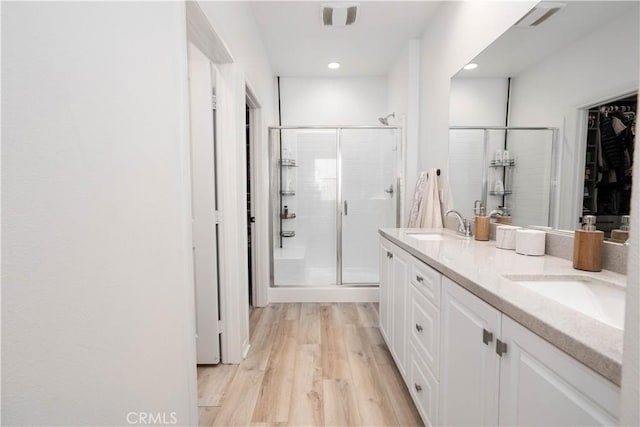 bathroom with hardwood / wood-style floors, a shower with door, and vanity