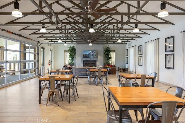 dining space featuring ceiling fan, vaulted ceiling with beams, plenty of natural light, and a large fireplace