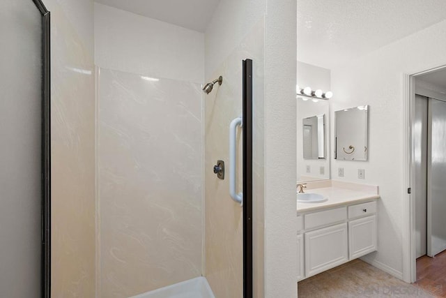 bathroom with wood-type flooring, walk in shower, and vanity