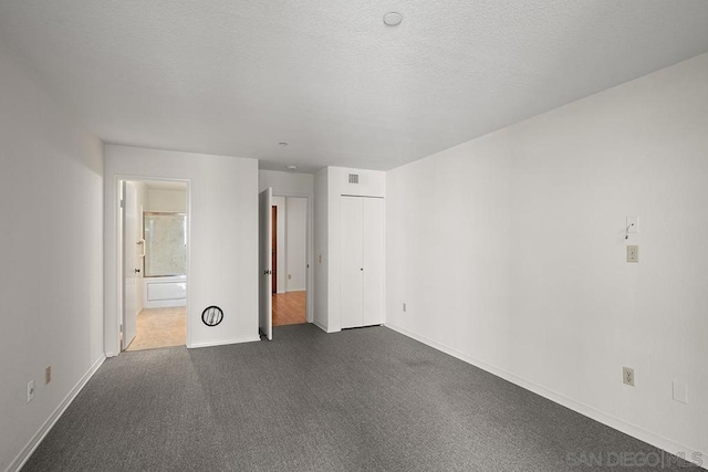 empty room with a textured ceiling and dark colored carpet