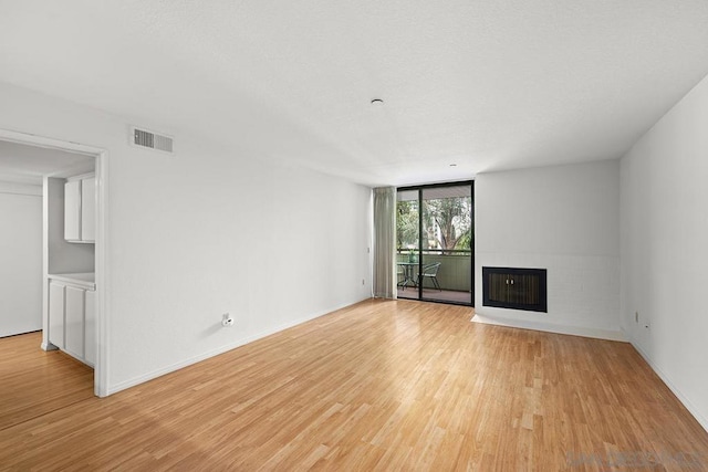 unfurnished living room featuring heating unit, floor to ceiling windows, and light hardwood / wood-style floors