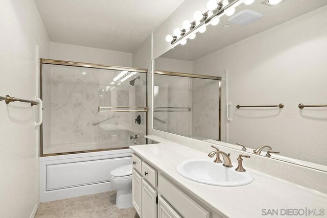 full bathroom featuring toilet, enclosed tub / shower combo, tile patterned floors, and vanity