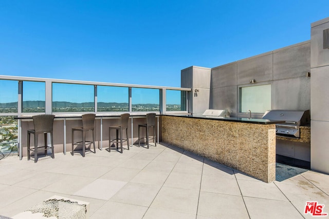 view of patio with exterior kitchen, a grill, a mountain view, and an outdoor wet bar