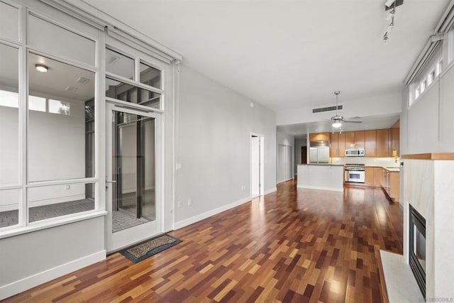 unfurnished living room with dark wood-type flooring, rail lighting, a fireplace, and ceiling fan