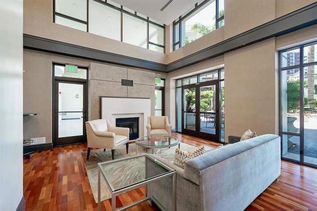 living room featuring french doors, a towering ceiling, and wood-type flooring