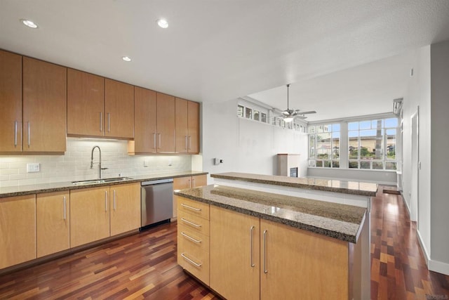 kitchen featuring ceiling fan, dark wood-type flooring, dishwasher, a kitchen island, and sink