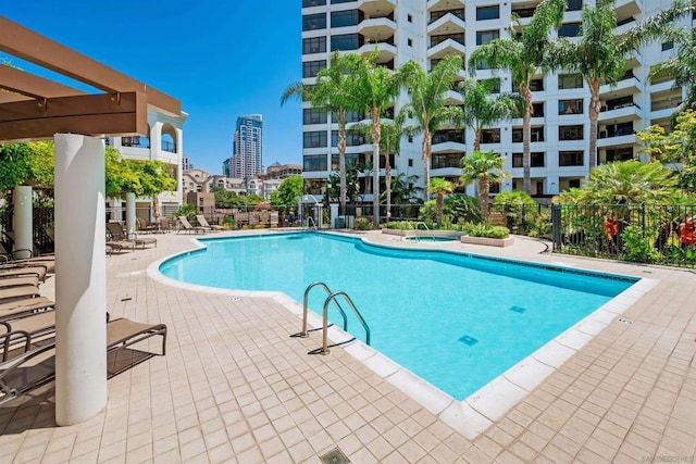 view of pool with a community hot tub, a pergola, and a patio