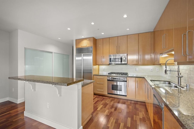 kitchen featuring backsplash, dark hardwood / wood-style floors, a breakfast bar, sink, and stainless steel appliances