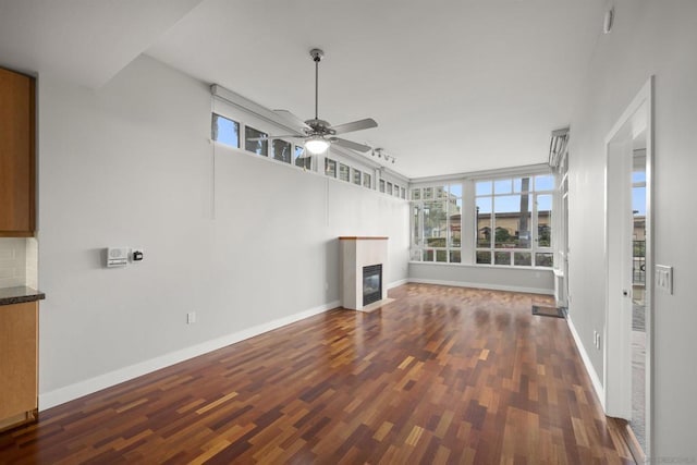 unfurnished living room featuring ceiling fan and dark wood-type flooring