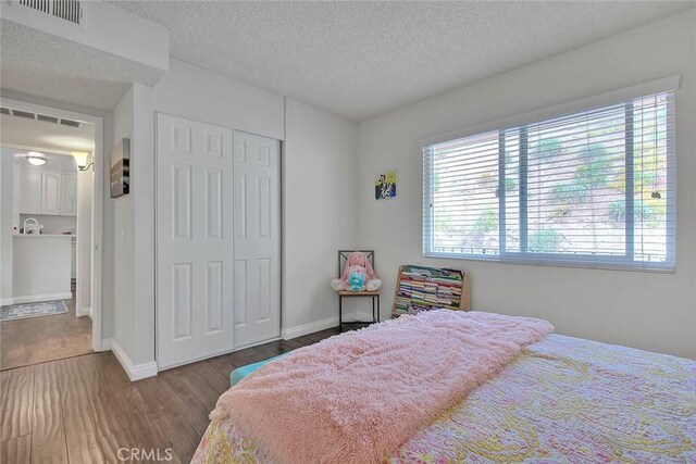 bedroom featuring a textured ceiling, a closet, and hardwood / wood-style floors