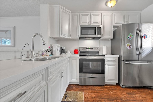 kitchen featuring light stone countertops, appliances with stainless steel finishes, white cabinetry, dark hardwood / wood-style flooring, and sink